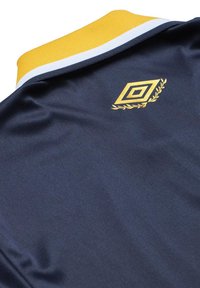 Polo sportiv de culoare bleumarin cu un guler cu dungi galbene și albe. Prezintă un logo auriu și un design cu lauri în zona pieptului. Textură netedă.