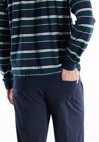 Navy-striped long-sleeve shirt with green and white stripes; features a cuffed hem and a relaxed fit; paired with navy pants that have side pockets.