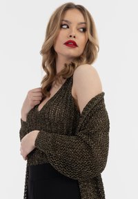 Svart, öppenstickad, oversized k cardigan med metalltrådar, lager på ett åtsittande linne. Långa ärmar och djup V-ringning.