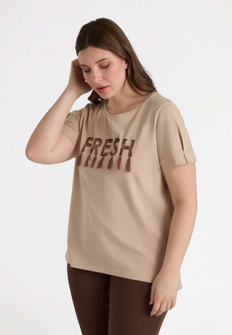 Camiseta de manga corta beige con el texto bordado "FRESH" en marrón, que presenta un cuello redondo y acentos de manga enrollada. Textura de tejido suave.