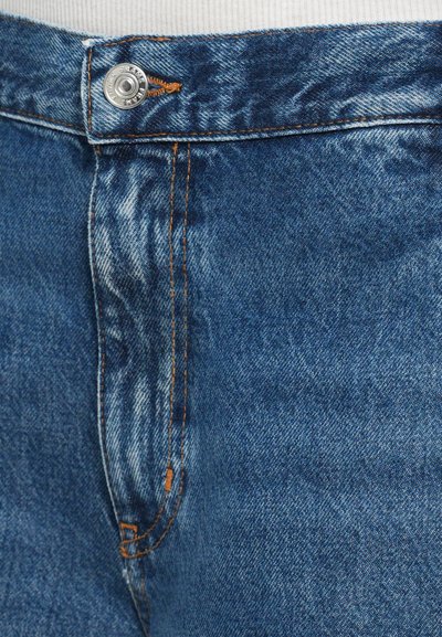 Modré džíny z denimu mají zapínání na knoflík, oranžové švy a opraný vzhled, který zdůrazňuje klasický design s pěti kapsami.