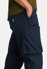 Navy cargo pants van duurzaam materiaal, met een zijzak en Timberland logo patch, met een rechte snit en een gladde textuur.