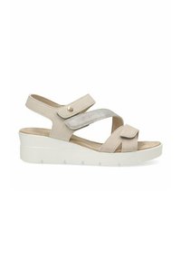 Sandalia beige con tiras cruzadas, acentos elásticos y puntera redondeada. Cuenta con una suela de plataforma blanca y un botón decorativo de metal.