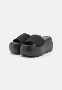 Sorte platform slide sandaler med tykke såler og brede stofremme, præsenteret på en hvid baggrund.