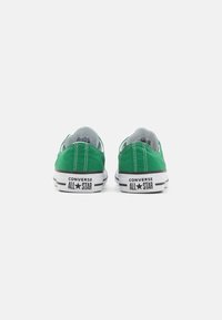 Tenisi verzi din pânză cu un design low-top, talpă din cauciuc alb și accente negre, având logo-ul "Converse All Star" pe toc.