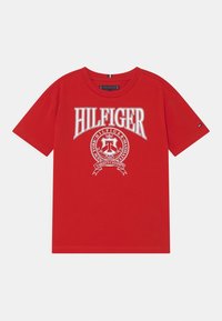 Czerwona koszulka z krótkim rękawem z białym napisem "Hilfiger" oraz okrągłym emblematem z detalami "Varsity Champs" i "Nowy Jork Manhattan".