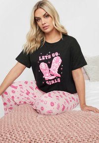 Svart t-shirt med "LET'S GO GIRLS" i rosa, parat med rosa pyjamasbyxor med mönster av cowboyboots och stjärnor. Mjuk tyger, avslappnad passform.