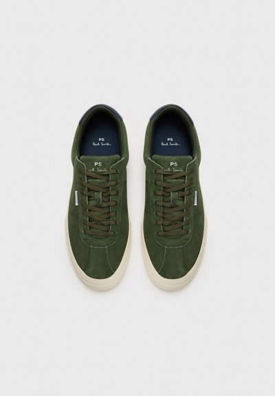Adidași verzi din suede cu o textură netedă, vârful rotunjit, șireturi asortate și o talpă din cauciuc crem. Prezintă un accent bleumarin la călcâi.