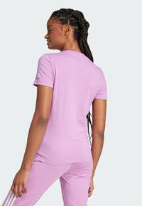 Jasnoróżowy sportowy t-shirt z krótkim rękawem, okrągłym dekoltem i subtelnym logo na lewym rękawie. Miękka, gładka faktura tkaniny.