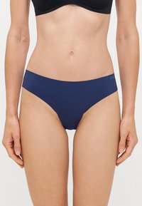 Navy blue bikini briefs with smooth fabric, mid-rise design, and subtle brand logo on the waistband. Offers minimal coverage and sleek shape.