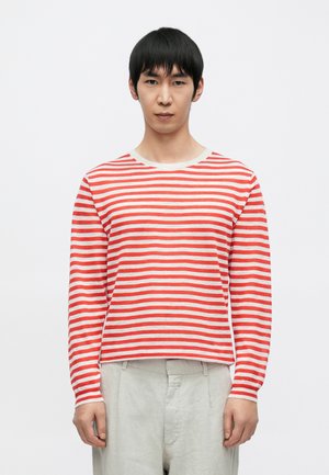 Camisa de manga larga a rayas rojas y blancas con cuello redondo, de corte relajado y textura suave, combinada con pantalones de color claro.