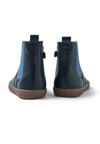 Botas de tobillo de cuero azul oscuro con paneles laterales elásticos, puntera redondeada y suela de goma marrón. La parte trasera cuenta con tiradores y detalle de logo.