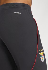 Zwarte sportshorts met rode zijkanten. Voorzien van Aeroready branding en het Benfica clubembleem met drie sterren. Glad, lichtgewicht materiaal.