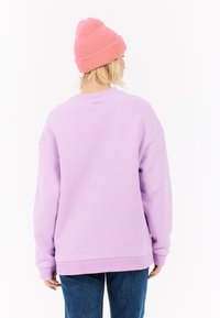 Sudadera de color púrpura claro con un corte relajado, puños acanalados y un cuello redondo, combinada con un gorro de punto rosa. Material de mezcla de algodón.