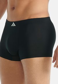 Svarta atletiska boxershorts med en slät yta, en tajt passform och en liten vit Adidas-logotyp på midjebandet.