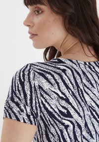 Granatowa i biała bluzka z krótkim rękawem, z wzorem w paski przypominającym zwierzęcy, wykonana z miękkiego materiału w luźnym kroju.