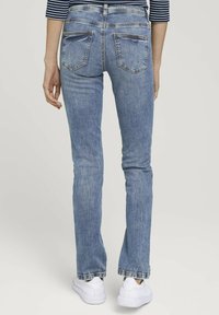 Jeans in denim azzurro fitted, con un classico design a cinque tasche, leggera sfumature e una leggera flare all'orlo, abbinati a sneaker bianche.