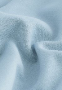 Țesătură de un albastru deschis, cu o textură moale și netedă, având un model fin de tricot, aranjată pentru a evidenția pliurile și mișcarea.
