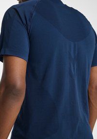 Marinblå atletisk skjorta med korta ärmar, med strukturerade paneler och en slät yta, designad för komfort och prestanda.