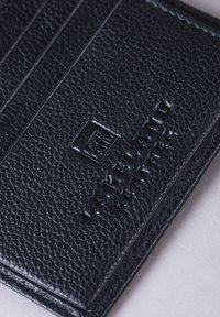 Black leather card holder featuring a textured surface, embossed logo, and multiple card slots for organized storage. Compact and functional design.