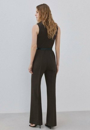 Brązowy kombinezon z dopasowaną górą i rozszerzanymi nogawkami, ozdobiony eleganckim czarnym paskiem, wykonany z gładkiej tkaniny o strukturalnym kroju.