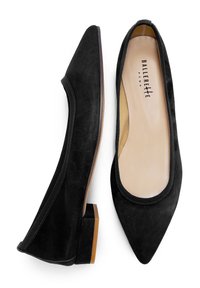 Mocasines de ballet de ante negro con un diseño de punta, bordes elásticos y un tacón bajo de bloque con una suela lisa en tono marrón claro.