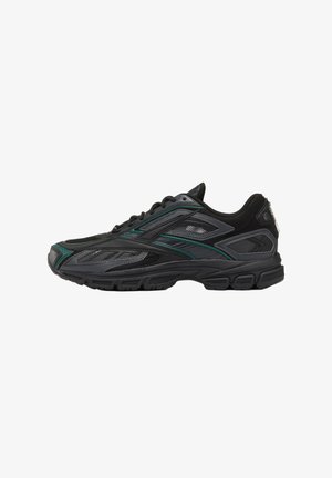 Schwarzer Sportschuh mit grünen Akzenten, Netzpaneelen und einer strukturierten Sohle, von der Seite auf weißem Hintergrund dargestellt.
