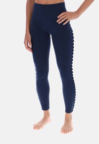 Tmavomodré legíny s vysokým pásom vyrobené z hladkého, elastického materiálu, s vlnkovými akcentmi po stranách pre dodanie vizuálneho detailu.