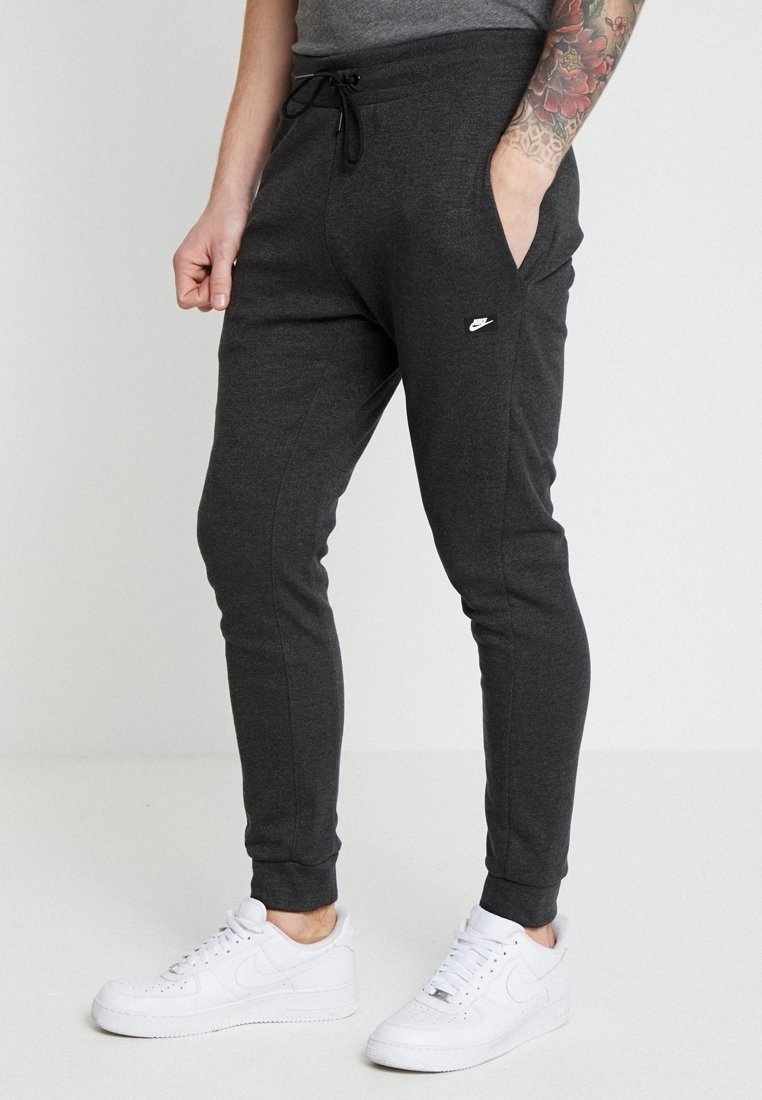 Grå joggerbyxor i mjukt tyg, med sidofickor, dragsko i midjan och en liten vit logotyp på vänster höft.