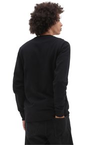 Sudadera negra de manga larga, con cuello redondo y puños y dobladillo de canalé. Fabricada en una suave tela de textura lisa.
