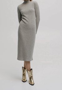 Robe midi en tricot côtelé gris avec des manches longues et un col montant, assortie à des bottes de cowboy dorées métalliques à bouts pointus.