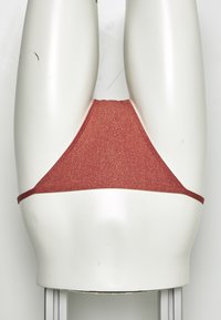 Parte de baixo de bikini vermelha com glitter, em forma triangular e com tiras laterais finas, exibida em um manequim branco contra um fundo neutro.