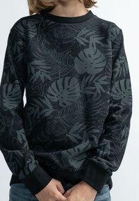 Černá mikina s tmavě zeleným tropickým vzorem lístků, kulatým výstřihem, dlouhými rukávy a žebrovanými manžetami. Měkká textura, volný střih.