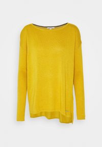 Gul långärmad tröja med lös passform, ribbade ärmar och rundad fåll. Har en etikett på den nedre sidan för varumärkesidentifikation.