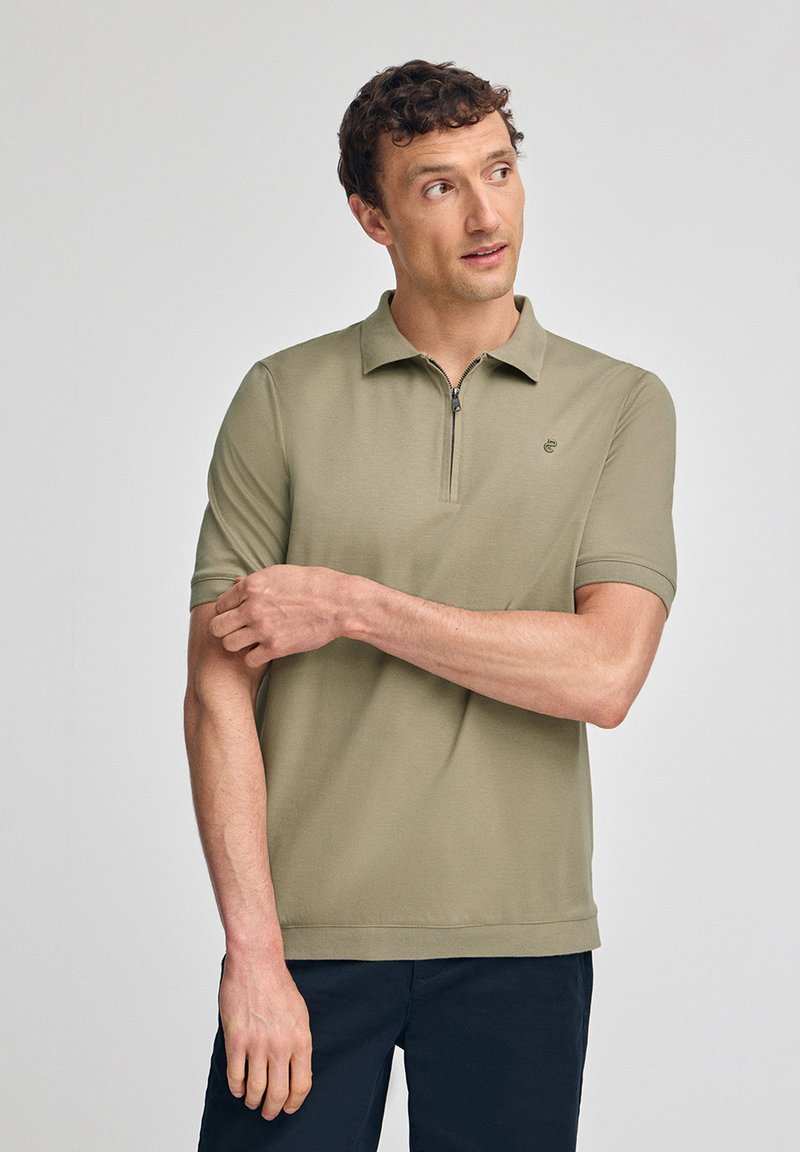 Kortärmad, olivgrön polo med dragkedja och broderad logotyp. Slätt tyg och rak fålldesign.