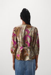 Multicolored blouse featuring intricate paisley and geometric patterns, with puff sleeves, a cinched waist, and a smooth satin-like texture.