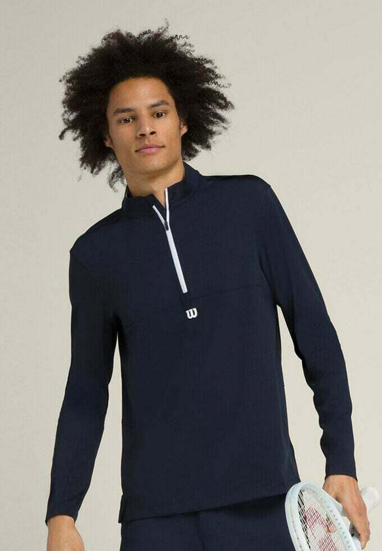Pullover sportivo blu navy a maniche lunghe con mezzo zip, zip bianca e piccolo logo bianco sul petto. Tessuto morbido e leggero.