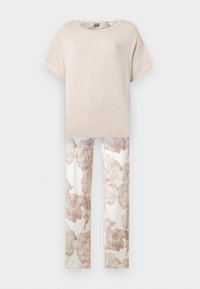 Haut beige à manches courtes associé à un pantalon blanc présentant de grands motifs floraux taupe, affiché sur un fond blanc uni.