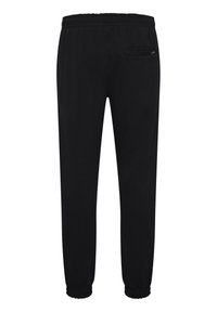 Pantalones de chándal negros con una cinturilla elástica, puños ajustados y un pequeño bolsillo trasero en el lado derecho. Textura de tela suave.