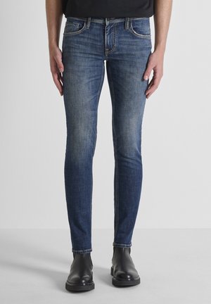 Jean skinny en denim bleu foncé avec un léger délavage. Doté d'un design classique à cinq poches, de coutures contrastantes et de quincaillerie en ton argent.