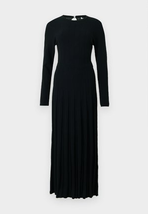 Vestido preto de manga longa feito de tecido de malha canelada, apresentando um corpete justo e uma saia rodada com pregas. Fecho nas costas com um pequeno botão.