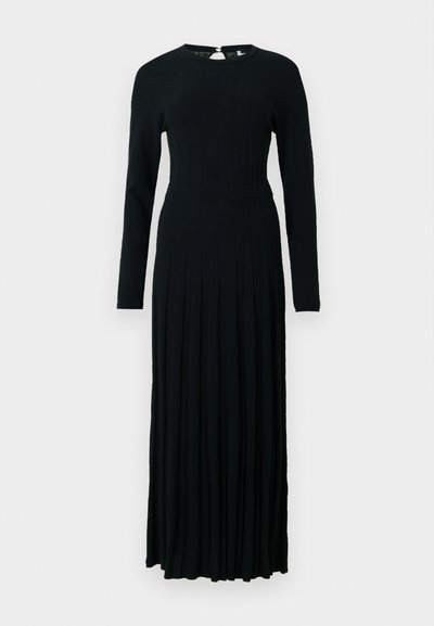 Vestido preto de manga longa feito de tecido de malha canelada, apresentando um corpete justo e uma saia rodada com pregas. Fecho nas costas com um pequeno botão.