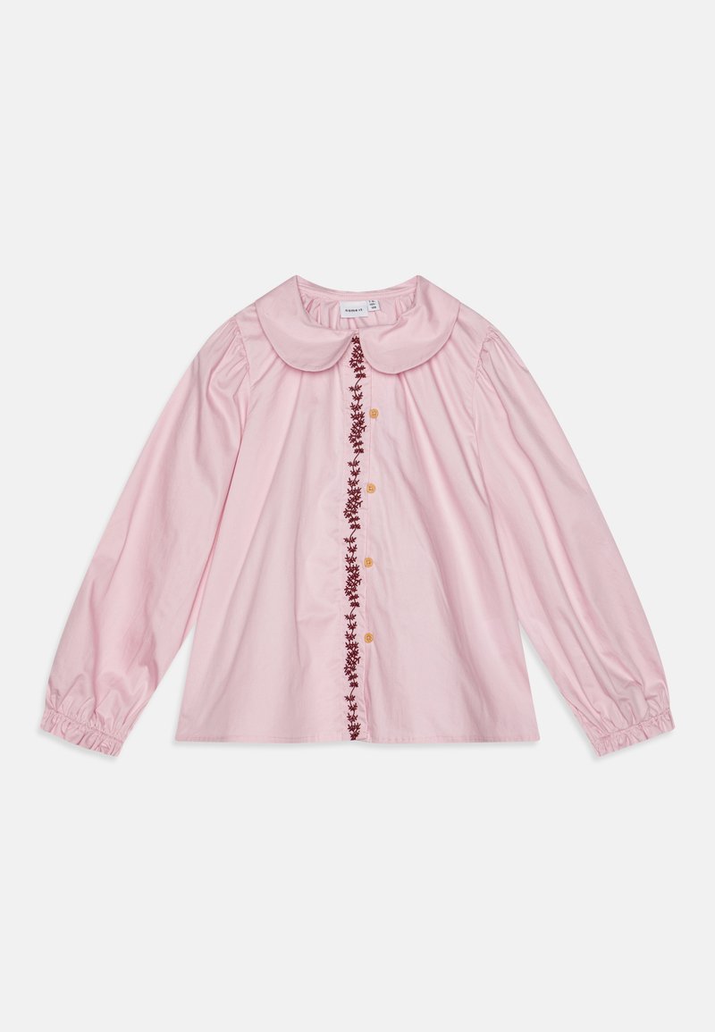 Roza majica z dolgimi rokavi in okroglim ovratnikom, z ročno vezenimi cvetlicami po sredini in gumbi v kontrastni barvi.