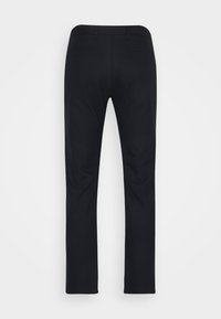 Pantalon noir slim-fit vu de dos avec deux poches passepoilées et sans fermetures ni ornements visibles.