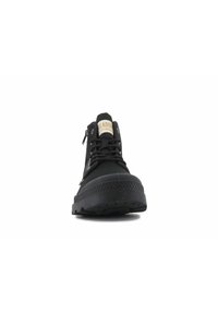 Zapatilla alta negra con parte superior de lona suave, suela de goma, cordones y una cremallera lateral; presenta un diseño texturizado en la suela.