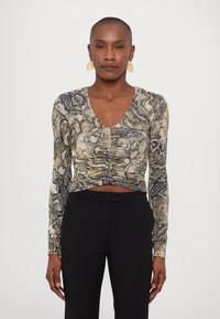 Maglietta aderente a maniche lunghe con una stampa a serpente nei toni beige, nero e marrone. Scollo a V con dettaglio arricciato in vita.