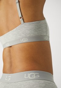 Sivi UGG bralet bez šavova, s mekim texture tkanine i logotip trakom na dnu. Uključene podesive naramenice.