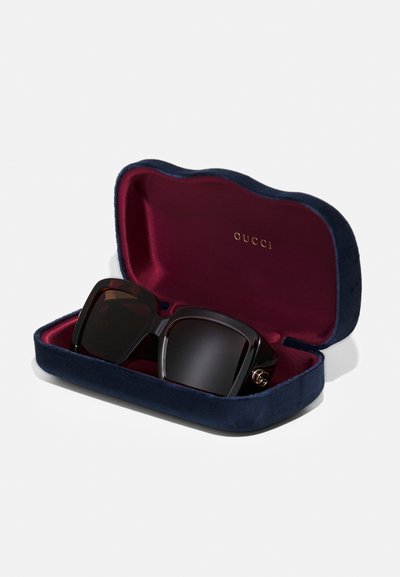 Gucci prillid sametist tumesinises karbis, mille sees on burgundia toon. Omavad suuri musti raame ja kuldset logoaktsenti küljel.
