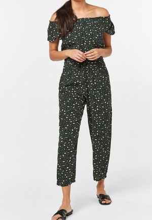 Kombinezon z odkrytymi ramionami w ciemnozielonym kolorze z kremowo-czarnym wzorem w panterkę. Posiada elastyczną talię i nogawki sięgające kostek. Gładka tekstura materiału.
