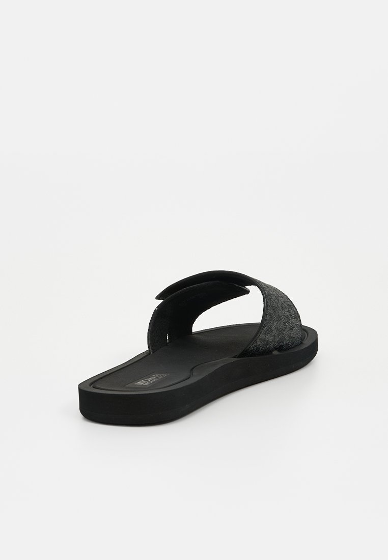 Chanclas negras con una parte superior de tejido texturizado y suela de goma plana, que presentan un talón abierto y una barra de dedo curvada para mayor comodidad.